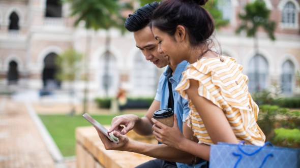 A couple are looking at a phone; image used for HSBC Malaysia Amanah Mobile Banking page