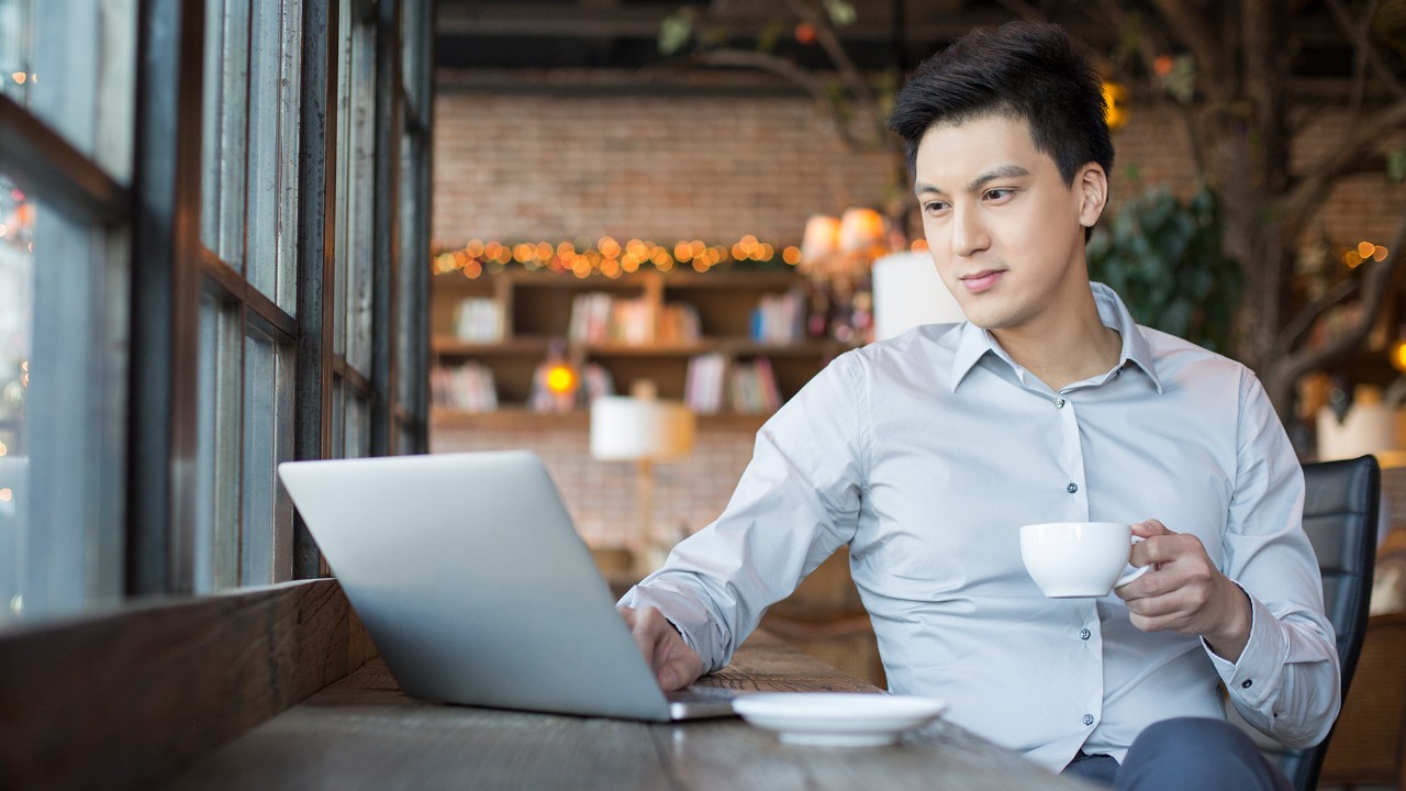 A man drinking coffee and working on his laptop; image used for HSBC term deposit-i page.