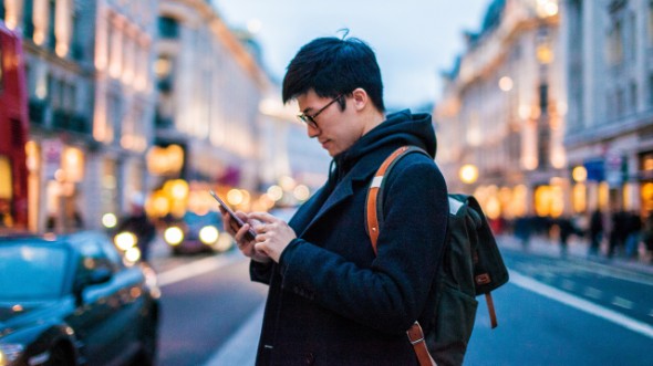A man is looking at his phone; image used for HSBC Malaysia Amanah online banking