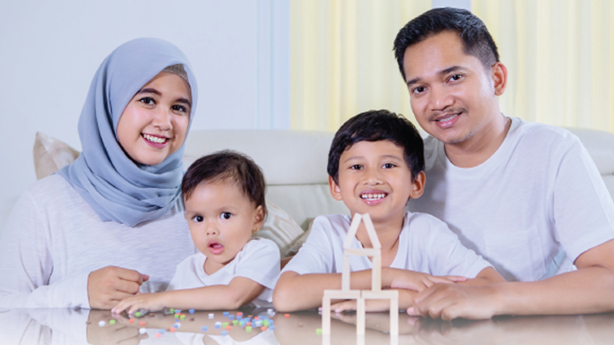 Man, woman and 2 children in a living room; image used for HSBC Malaysia and MyKNP financial help page.