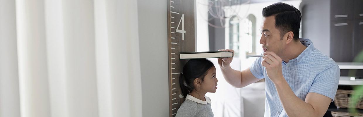 Father measuring his daughter's height; image used for HSBC Malaysia Amanah Basic Savings/Current Account-i page.