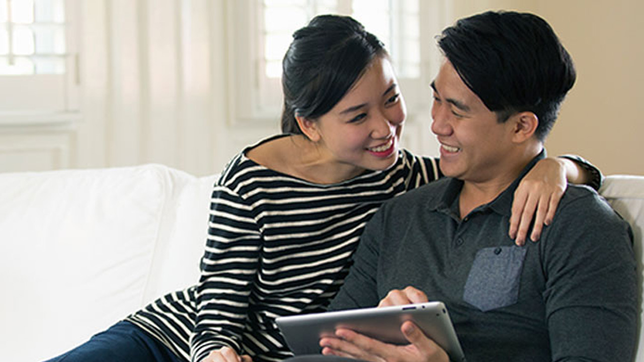 A couple is using tablet at home; image used for HSBC Amanah digital account opening page.