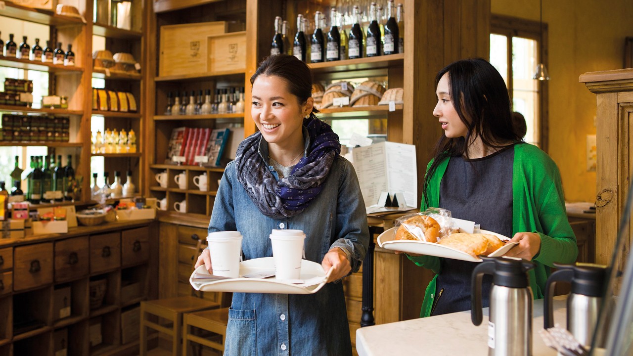 Two women carrying trays in a cafe; image used for HSBC individual expertise and support page.
