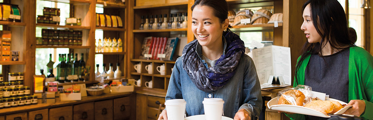 Two women carrying trays in a cafe; image used for HSBC individual expertise and support page.