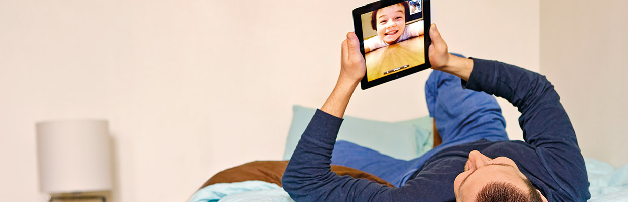 A man is on a video call from his bed; image used for HSBC online and on your side page.
