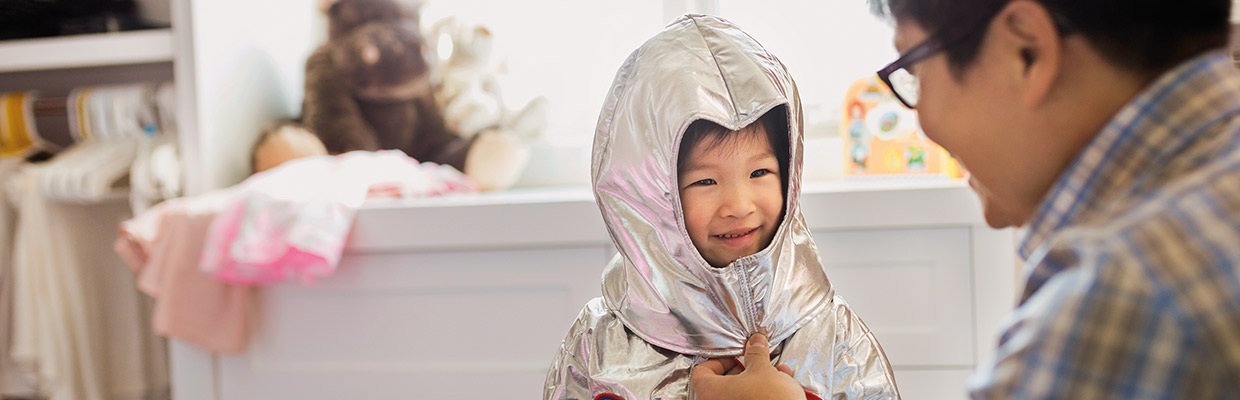 A little girl in an astronaut costume is smiling at her father; image used for HSBC Advance page