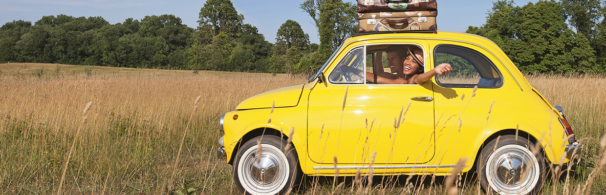 A woman driving a yellow car with suitcases on top; image used for HSBC faster access, more control page.