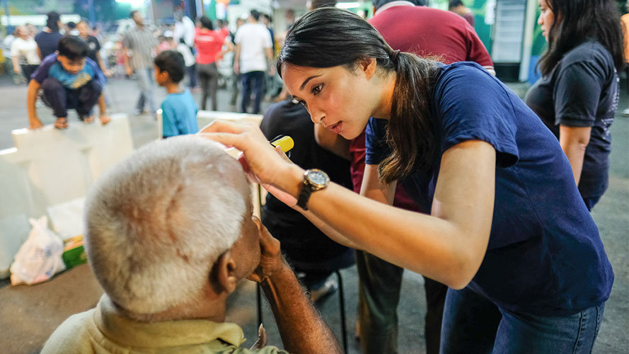 A volunteer help an old man to test eyesight; image used for HSBC Amanah Premier World Mastercard Credit Card-i page.