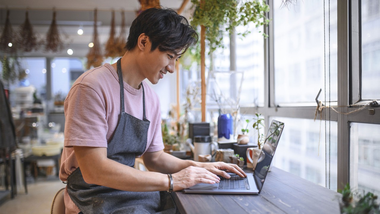 A man is using laptop in a coffee shop; image used for HSBC Amanah transfer limit amendment.